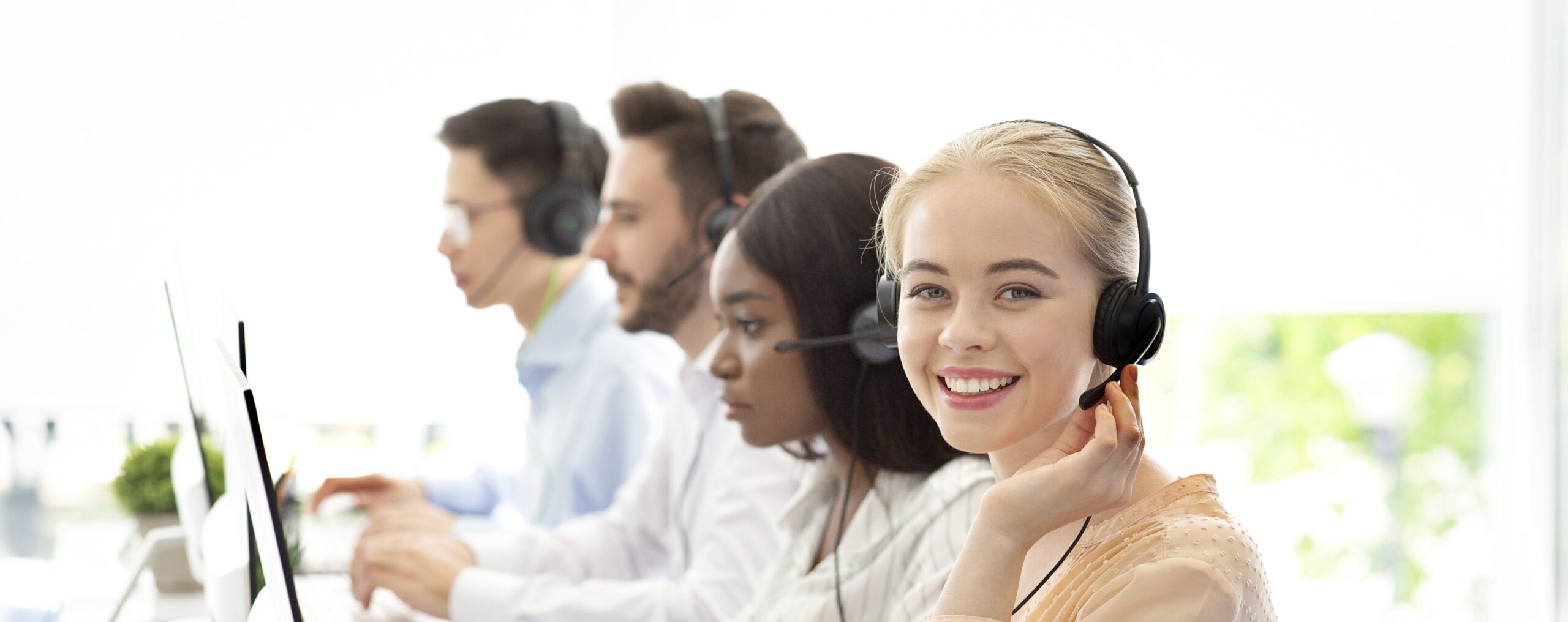 Lächelndes Kundenserviceteam mit Headsets im Büro